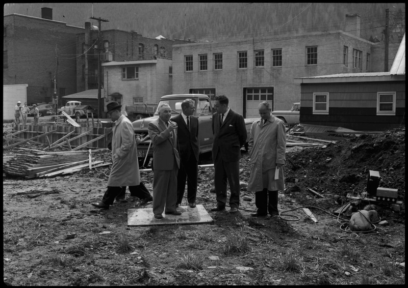 Four men standing and two men walking by near the construction of the Stardust Motel during its dedication.