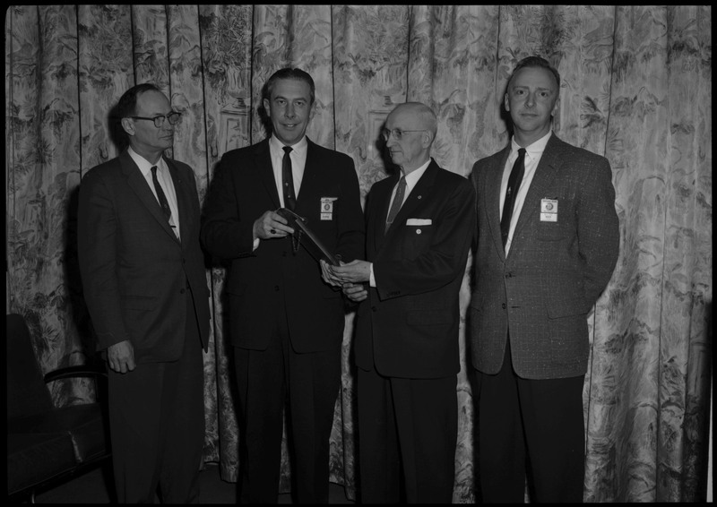 A man receiving the Frank Brewer award stands with three other men.