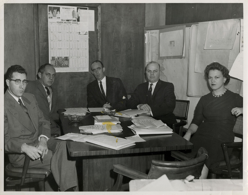 Four male and one female Wallace School Board members sit around a table. Papers are on the table and hang behind them.