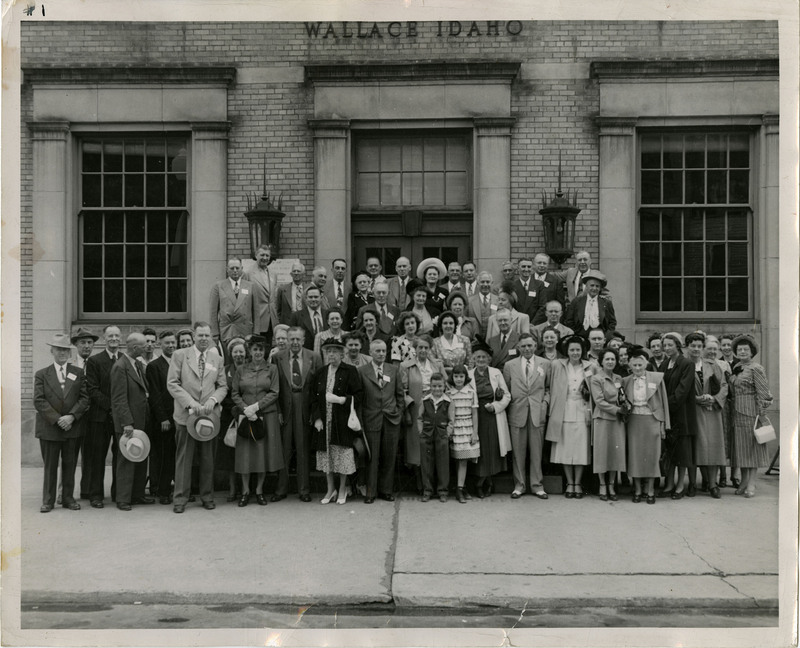 Unidentified men, women, and children in front of building in Wallace, Idaho. The words "Wallace, Idaho" are inscribed on the building.