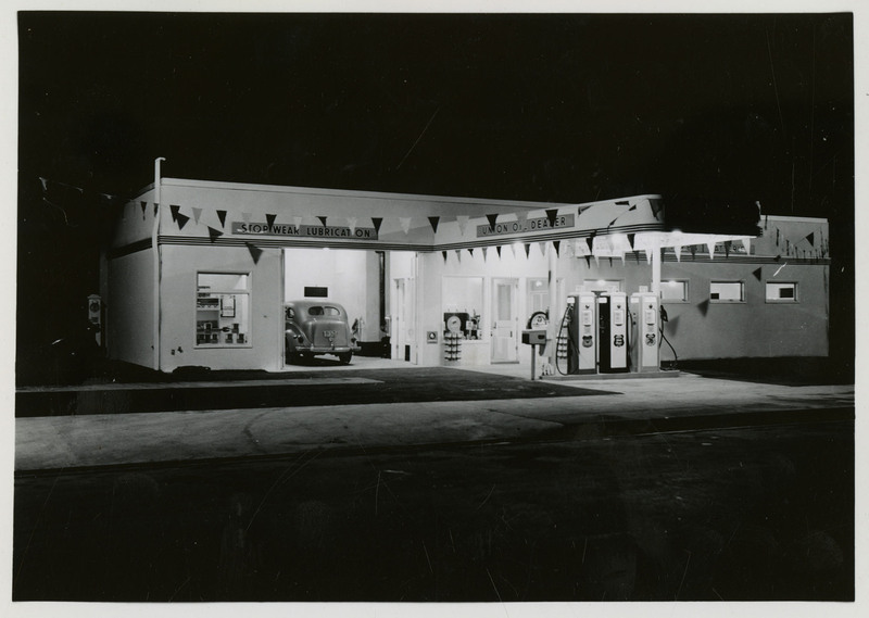 Union Oil Station and Bus Depot at night with lights on. A car is parked in the garage.