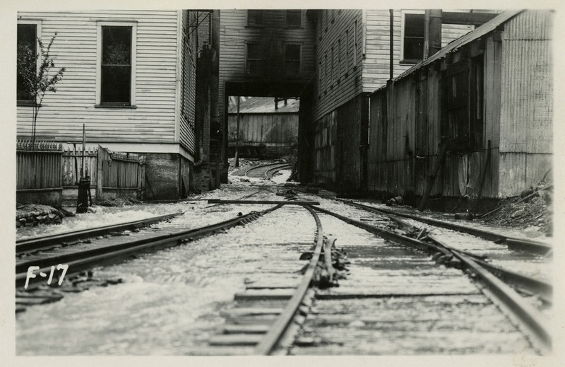 Railroad tracks running through Tiger Hotel, Burke, a ghost town. On verso reads "Tracks through the Tiger Hotel in Burke. Note the soot on the hotel above the tracks. Rom."