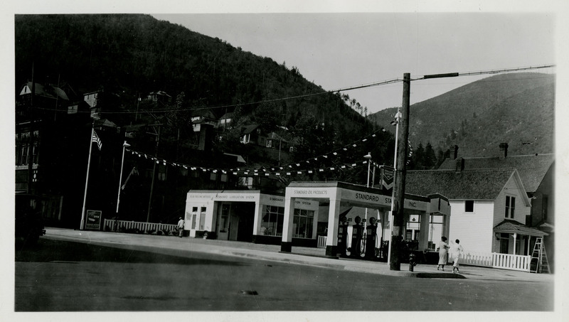 A view of the Standard Oil Company gas station. Trees and mountains can be seen in the background.