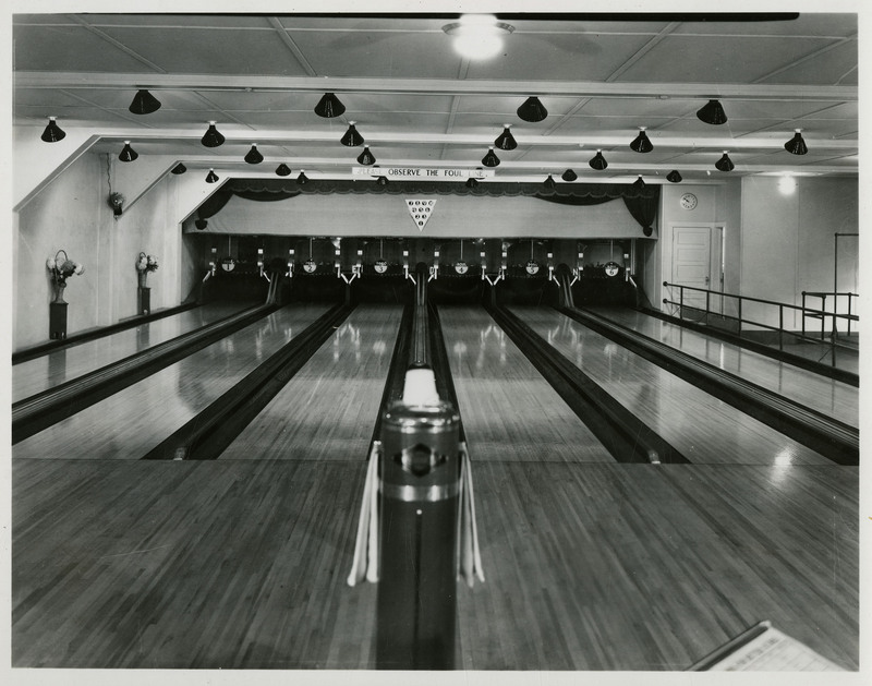 The interior of the Wallace bowling alley. A sign above the bowling lane reads "Please observe the foul line."