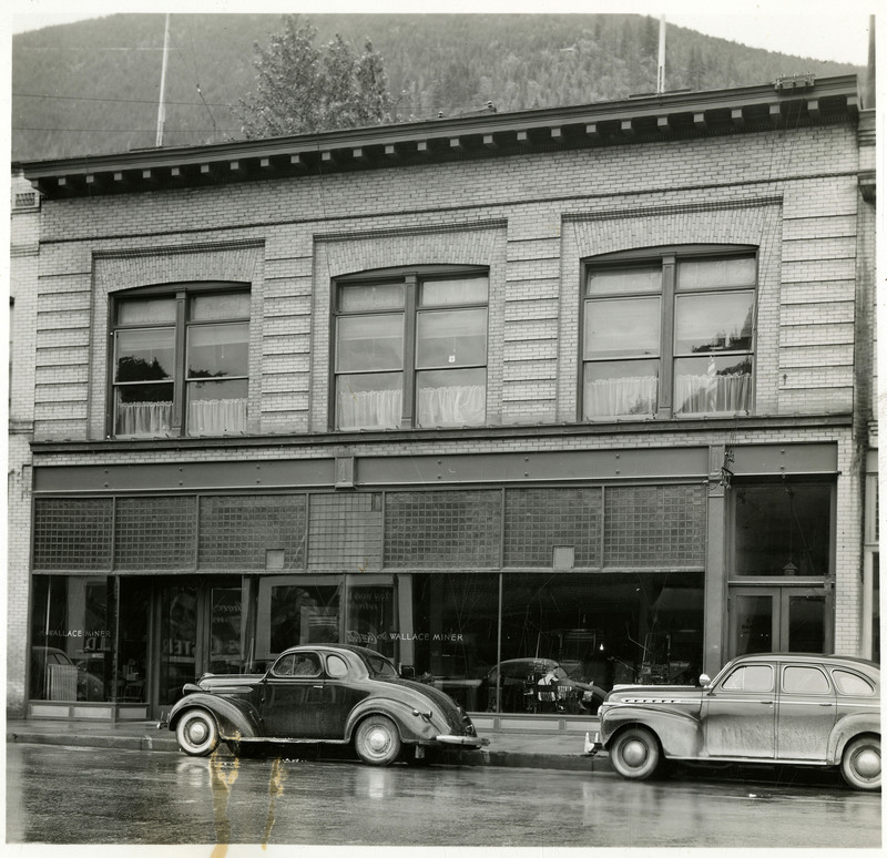 The Labor building on Bank Street in Wallace, Idaho. Two cars are parked in front of the building.