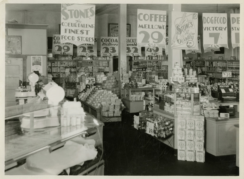 Displays inside the Stone's Grocery Store. Signs hang from the ceiling with various products and their prices.
