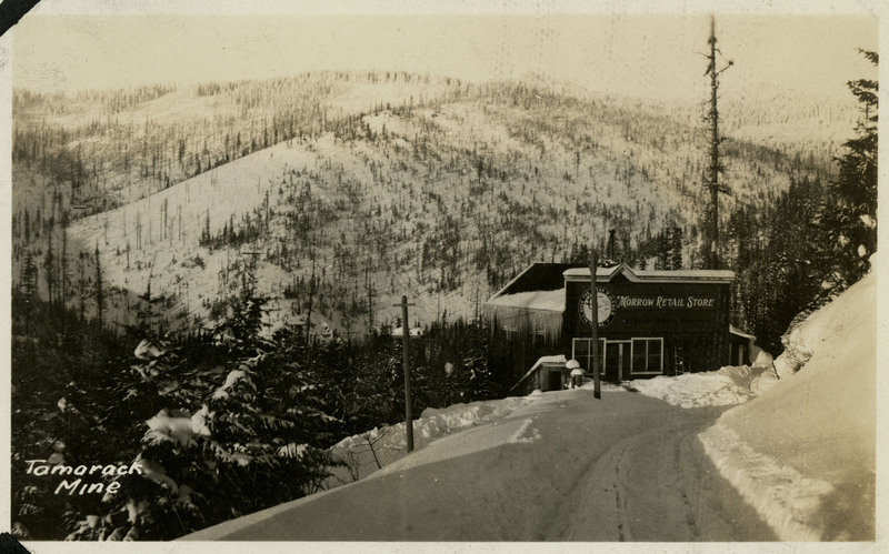 Postcard depicting a view of the Morrow Retail Store at the east fork of 9 Mile Creek Road. Bottom left of the postcard reads "Tamorack Mine." On verso reads "Built in 1917, Bill Mullan lived here."
