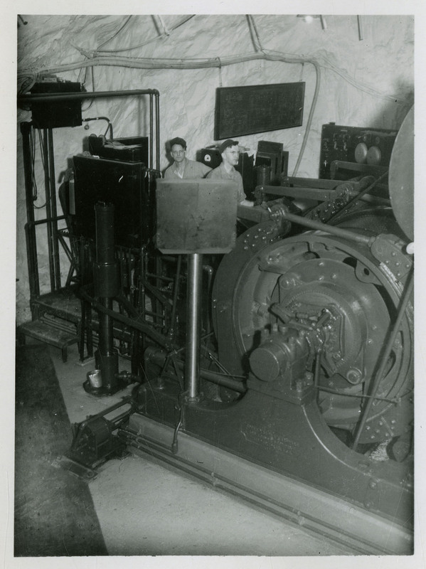 Two miners can be seen operating mining equipment in the hoist room.