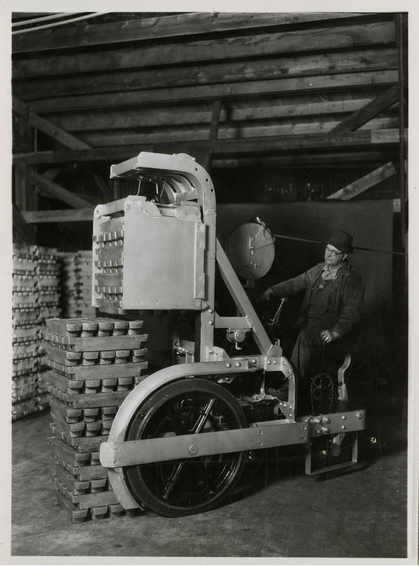 A man operating machinery to stack lead pigs for loading on to railroad cars.