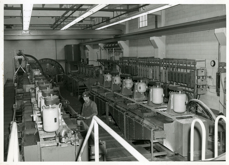 A worker in a large workroom with equipment and machinery.