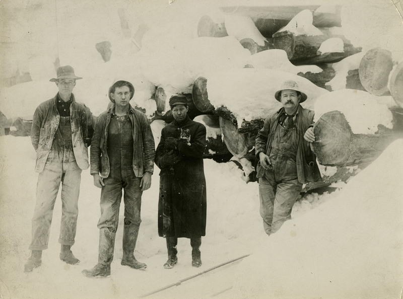 Miners standing in the snow. One of them is holding a cat.