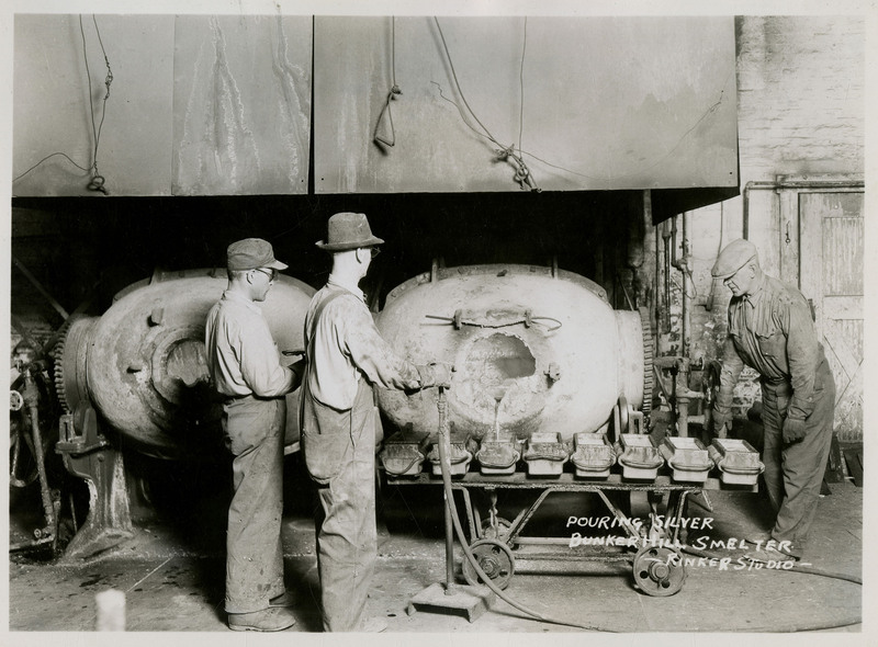 Three workers pouring silver bars at the Bunker Hill Smelter.