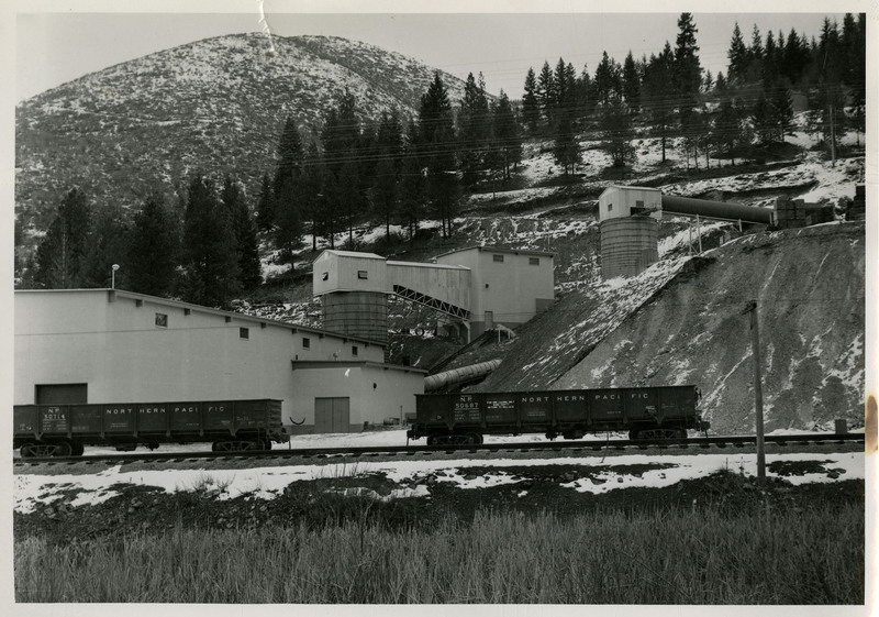 View of two railroad cars and buildings in the background at the Lucky Friday Mill in Mullan, Idaho.