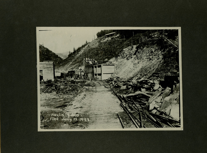 View of the aftermath of the Hecla Mine yard fire. Remnants of materials and buildings can be seen. Part of a mine railway is missing.