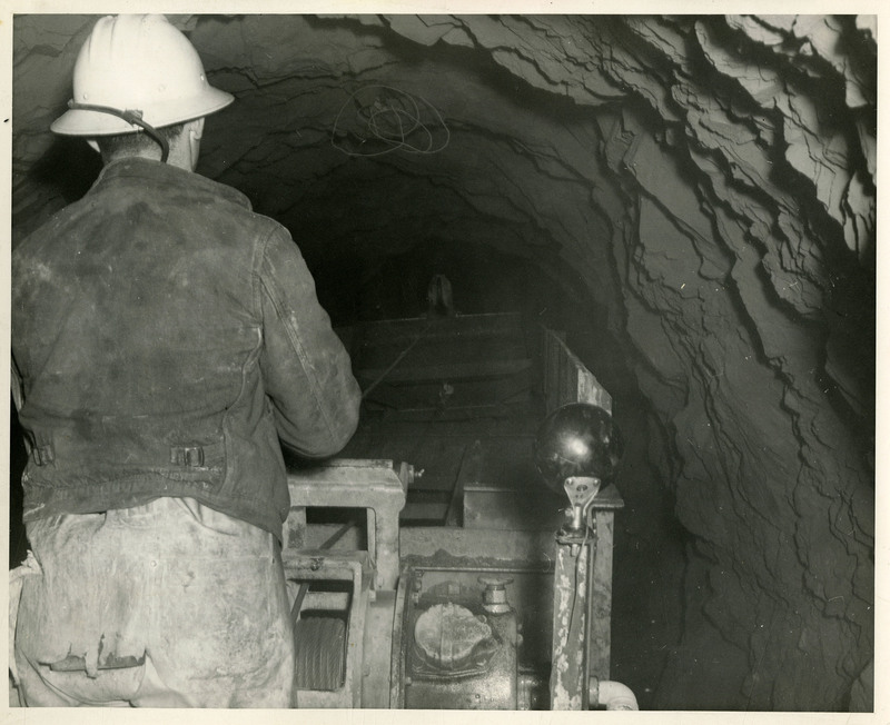 A miner operating mining machinery inside a mine.