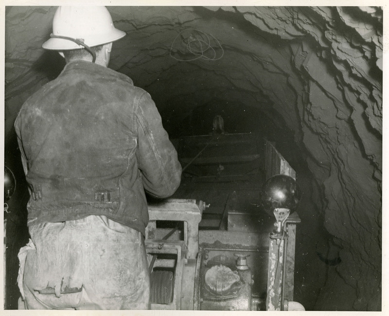 A miner operating mining machinery inside a mine.