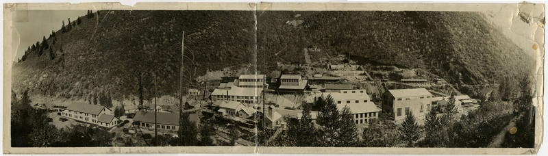 Panorama shot of an unidentified mine. Buildings can be seen at the bottom of a forested mountain.