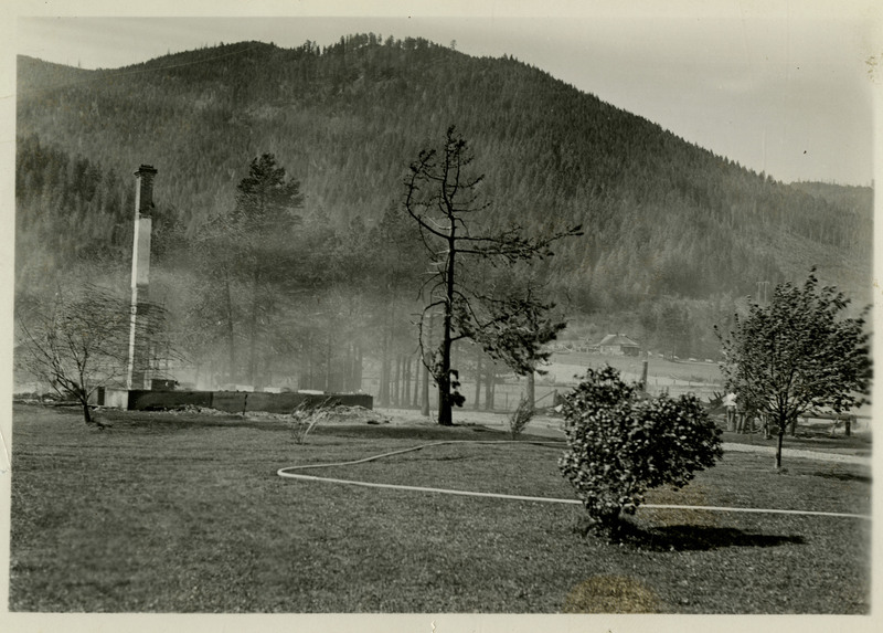 View of an unidentified location. Grassy lawn and a few trees are in the foreground. Trees and mountains in the background.