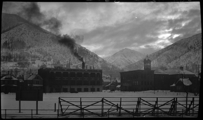 Photo of the Wallace, Idaho football field covered completely in snow. The bleachers sit between the photographer and the field, and beyond the field buildings and snow covered mountains can be seen.