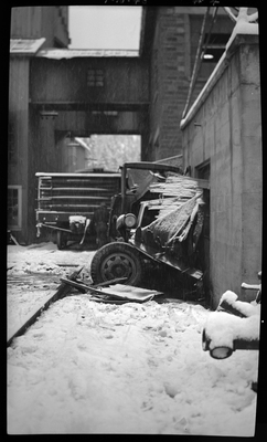 Photo of a damaged hardware truck that was hit by a Union Pacific train in Coeur d'Alene, Idaho. The front of the vehicle is visible and has been totaled by the train, and it appears to be leaning against a building. There is snow on the ground around the vehicles and building.