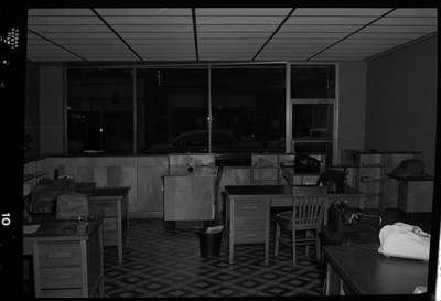 Photo of the interior of Citizens Utility Company office. There are several desks within the room, some of which have phones and typewriters on them.