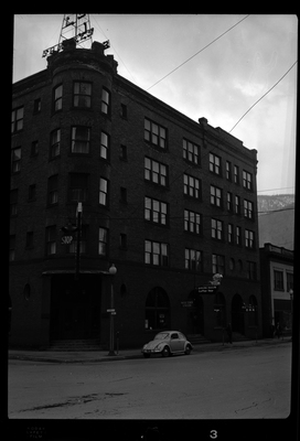 Photo of the right side of the building in which Samuel's Hotel is in, as well as the Western Union and Metal Bar. The building itself sits on the street corner and appears to be at least four stories tall. There is a car parked on the road next to the building.