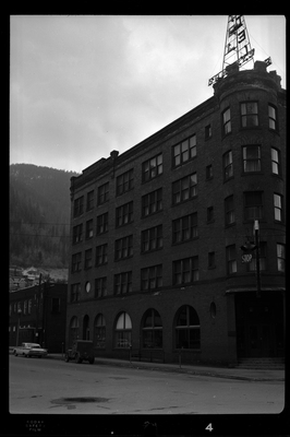 Photo of the left side of the building in which Samuel's Hotel is in. The building itself sits on the street corner and appears to be at least four stories tall. There are two cars parked on the road next to the building.