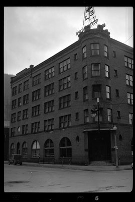Photo of the left side of the building in which Samuel's Hotel is in. The building itself sits on the street corner and appears to be at least four stories tall. There is a car parked on the road next to the building.