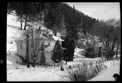 Photo of what appears to be a house in the snow. Described as "Standard Dairy, E. F. Gentry." There is a heavy layer of snow on the ground and the house is surrounded by trees, and more buildings a little further away.