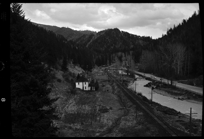 Photo of what appears to be a house in the distance. Described as "Standard Dairy, E. F. Gentry." The photo was taken from a higher elevation and looks down at the building from the side. There is a river that runs near by the building.