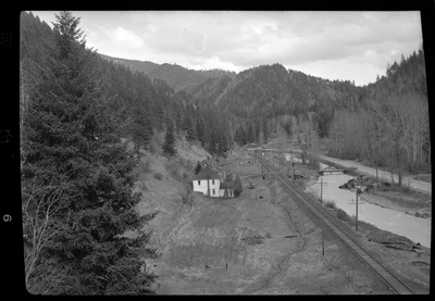 Photo of what appears to be a house in the distance. Described as "Standard Dairy, E. F. Gentry." The photo was taken from a higher elevation and looks down at the building from the side. There is a river that runs near by the building.