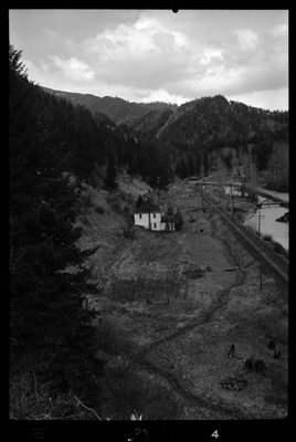 Photo of what appears to be a house in the distance. Described as "Standard Dairy, E. F. Gentry." The photo was taken from a higher elevation and looks down at the building from the side. There is a river that runs near by the building.