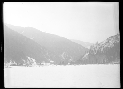 Photo of the city of Silverton, Idaho in the snow. The city sits in the distance from the photographer, and not much can be made out. The mountains surrounding the city are easily visible and are covered in trees and snow.
