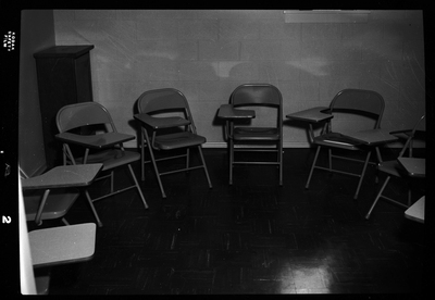Photo of a group of metal chairs with desk space arranged in a semi circle in a small room. They are within an Episcopal Church in Wallace, Idaho.