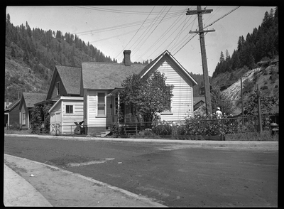 Photo of a home in Wallace, Idaho taken for Household Magazine. The photo was taken from the side of the house, showing the side yard and a tree that obscures most of the side of the house. It appears to be only one story tall.