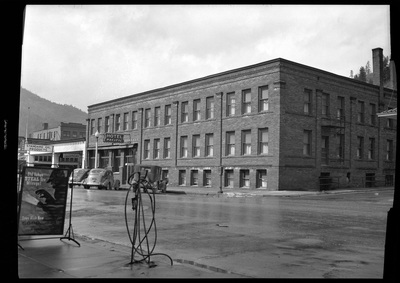 Photo of the Pacific Hotel (which sign reads "Hotel Pacific") building. There are several cars parked on the side of the road in front of it.