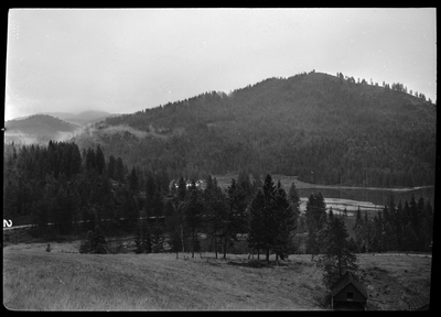 Scene from Revelli Ranch looking over some trees, hills, and a lake.