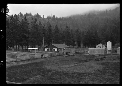 Scene from Revelli Ranch overlooking several empty livestock pens and a few buildings. There are also trees in the background.