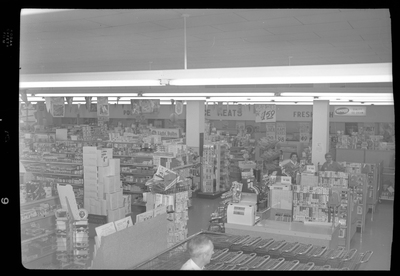 Photo of the interior of the Food Center Thrift Store. Stocked shelves line the room and a few people, including a cashier is visible.