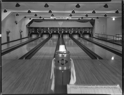 Photo of the Wallace Bowling Alley lanes looking towards where the pins are. There is a sign on the wall over the lanes that reads, "Please observe the foul line."