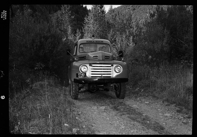 Two men from Shoshone County Search and Rescue are inside the search and rescue vehicle and presumably driving it down a dirt road. Front view of the vehicle shows the license plate number (3197) and that the men are seated in the front seats of the car.