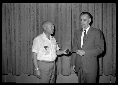 Two men together, exchanging a gavel. One man is Chamber of Commerce President Frank Kelso.