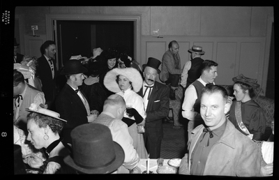 A group of people attending the Rotary Club party. Almost everyone pictured are dressed nicely and many are holding drinks. A few people are looking at the camera.
