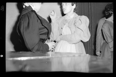 Candid photo of a woman at a Rotary Club party. She is talking to someone whose back is turned to the camera. Both women are well dressed.