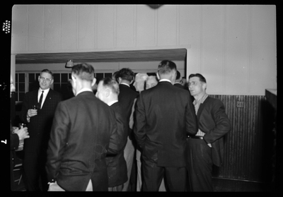 Blurry photo of men gathered together for an event for the Gyro District Governor. They are all dressed in suits.