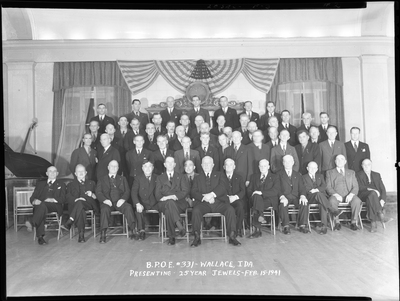 Men from Benevolent and Protective Order of Elks #331 sitting together for event "Presenting 25 Year Jewels." They are standing in rows with the front row seated, and they are all wearing suits.