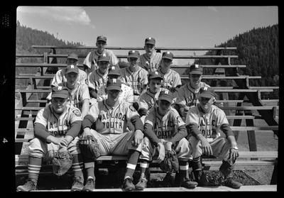 Group photo of the Wallace Youth Baseball team. The team are seated in rows on bleachers, wearing their uniforms and gloves. Previously described as "Legion baseball team all-stars."