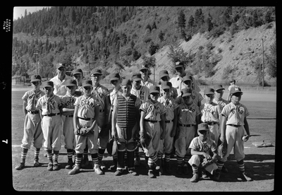 Group photo of the little league all-star baseball teams and their coaches. Most of the children are wearing matching baseball uniforms with various names on them: Rotary, Gyro, Hecla, Gene's.