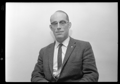 Photo of a man wearing a suit and glasses. Possibly Bill Featherstone.