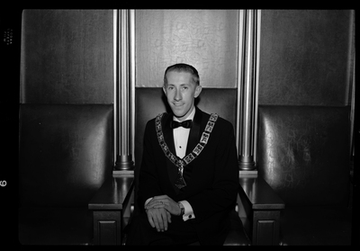 Photo of the Exalted Ruler of the Benevolent and Protective Order of Elks, Bob Wheeler. He is sitting in a chair, wearing a tuxedo, and a pendant.